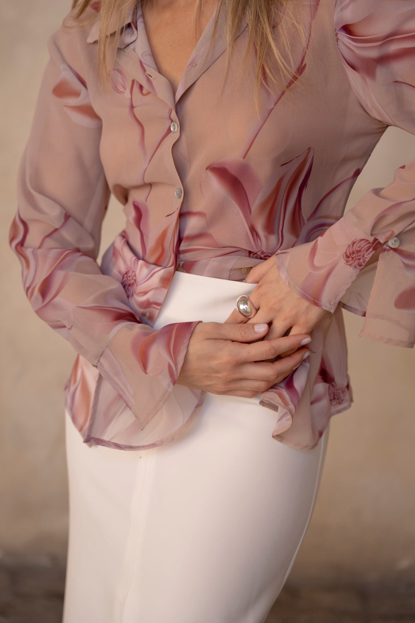 Γυναίκα που φοράει πουκάμισο floral ροζ από μουσελίνα. Είναι μακρυμάνικο και το έχει συνδυάσει με άσπρη pencil φούστα.