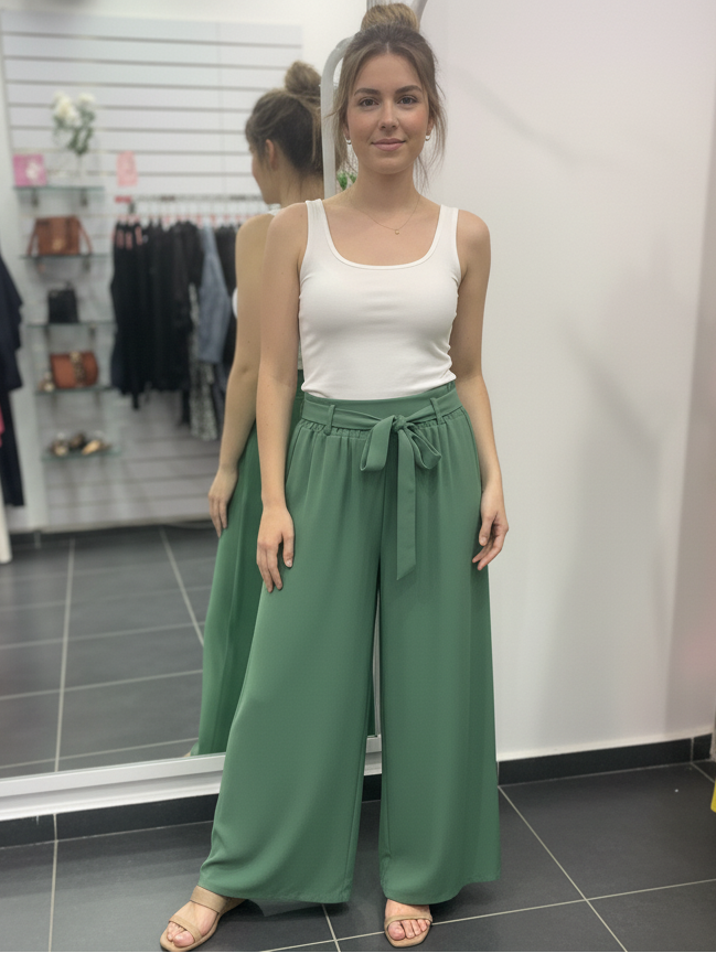 Γυναικείο παντελόνι φαρδύ σε πράσινο χρώμα. Στη μέση έχει λάστιχο και ζωνάκι από το ίδιο ύφασμα. Το μοντέλο το έχει συνδυάσει με λευκό φανελάκι