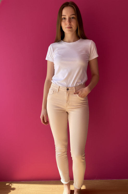 Μπεζ τζιν παντελόνι σε στενή γραμμή. Το μοντέλο το έχει συνδυάσει με λευκό t-shirt.  