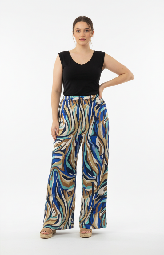 Παντελόνι σε σατέν ύφασμα με εμπριμέ σχέδιο σε μπλε, άσπρες και καφέ αποχρώσεις. Το μοντέλο την έχει συνδυάσει με μαύρο τοπ αμάνικο και πέδιλα